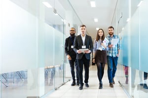 Full length of group of happy young business people walking the corridor in office together